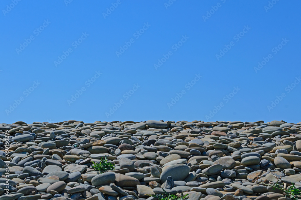 Gray stones on the seashore against the blue sky