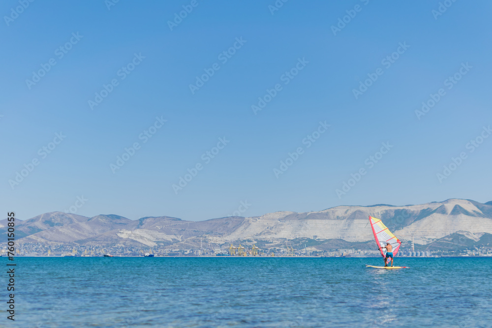 A man is engaged in windsurfing at sea, summer sea holidays, active recreation at sea