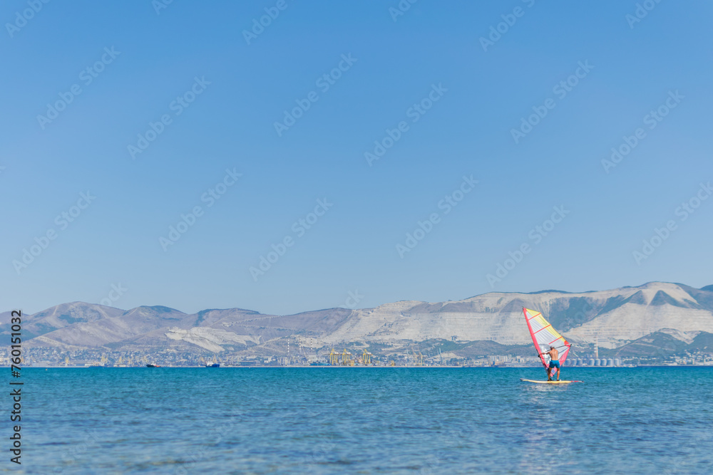A man is engaged in windsurfing at sea, summer sea holidays, active recreation at sea
