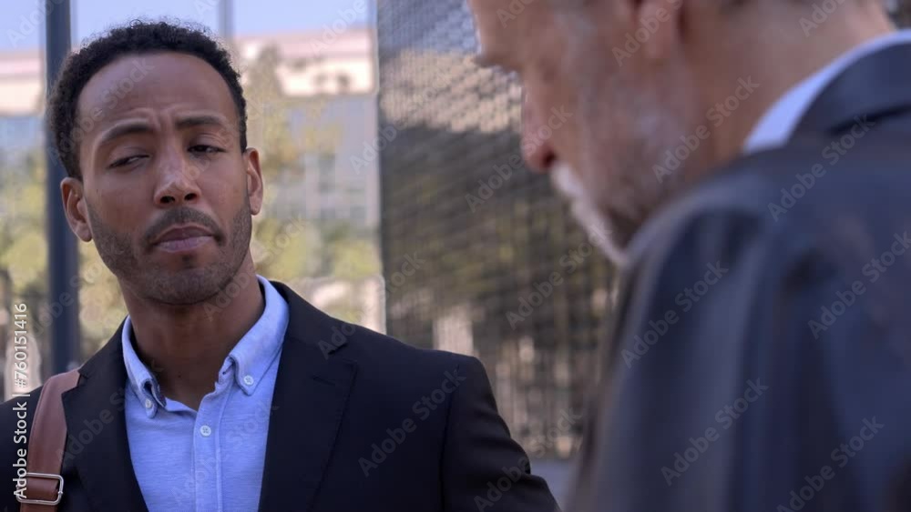 Two success adult business men converse standing on city street outside office talk from work about new projects. Professional Latin men meeting outdoors listen receptive his partner. Two success adult business men converse standing on city street outside office talk from work about new projects. Professional Latin men meeting outdoors listen receptive his partner.