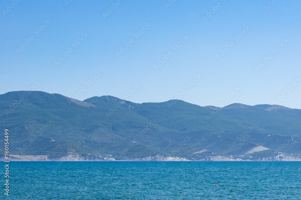 Sea horizontal landscape - blue sky, blue sea, mountain hills on the horizon
