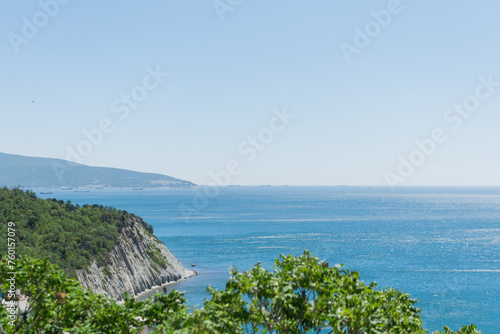 Obraz na płótnie Landscape of the blue sea with a green high coast against the blue sky on a sunny day w salonie