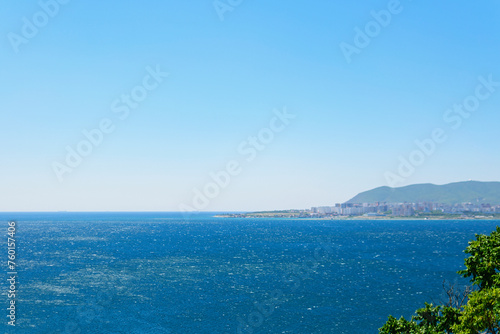 Obraz na płótnie Landscape of the blue sea with a green high coast against the blue sky on a sunny day w salonie