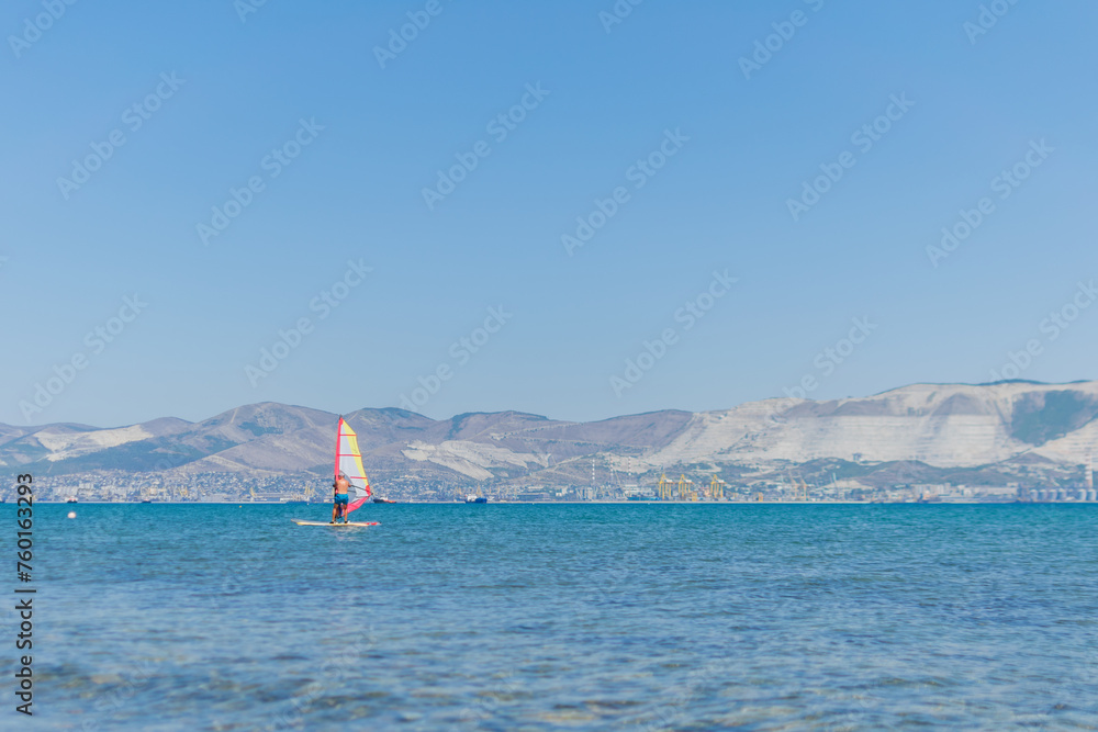 A man is engaged in windsurfing at sea, summer sea holidays, active recreation at sea