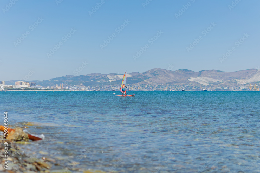 A man is engaged in windsurfing at sea, summer sea holidays, active recreation at sea