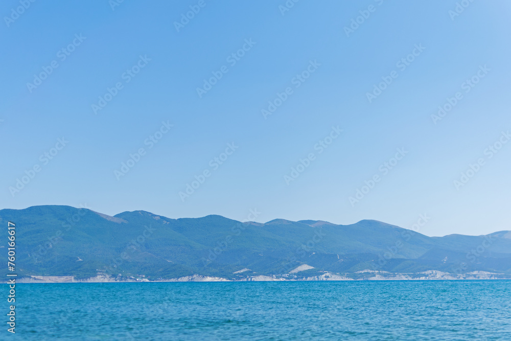 Sea horizontal landscape - blue sky, blue sea, mountain hills on the horizon