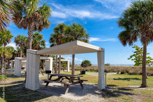 Picnic tables and shelters at the Siesta Key Beach in Florida, where visitors can enjoy a picnic under palm trees in ocean beach.