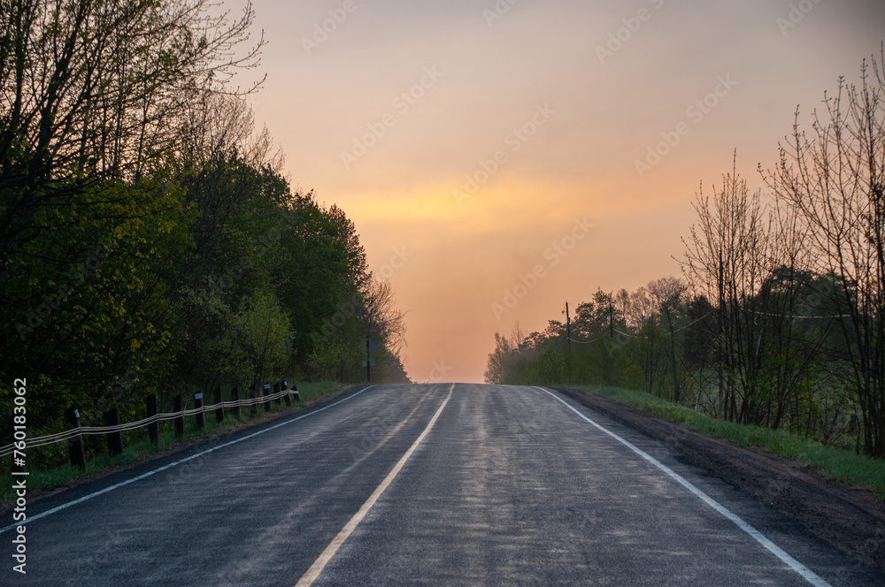 A hazy sunrise over a country road in the spring