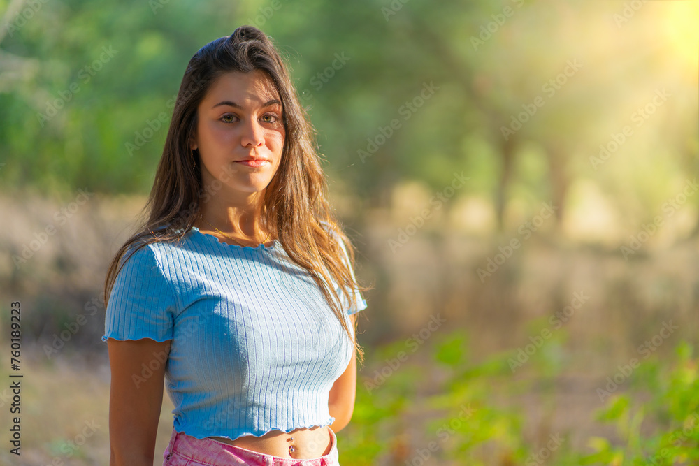 A woman is standing in a field with a blue shirt and pink skirt A woman is standing in a field with a blue shirt and pink skirt