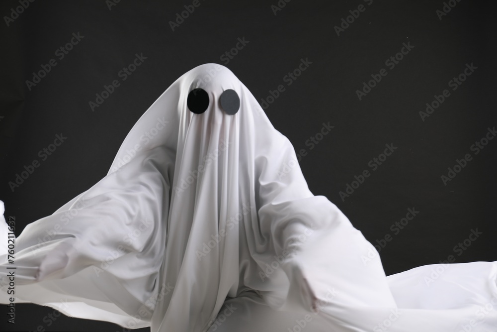 Creepy ghost. Person covered with white sheet on black background Creepy ghost. Person covered with white sheet on black background