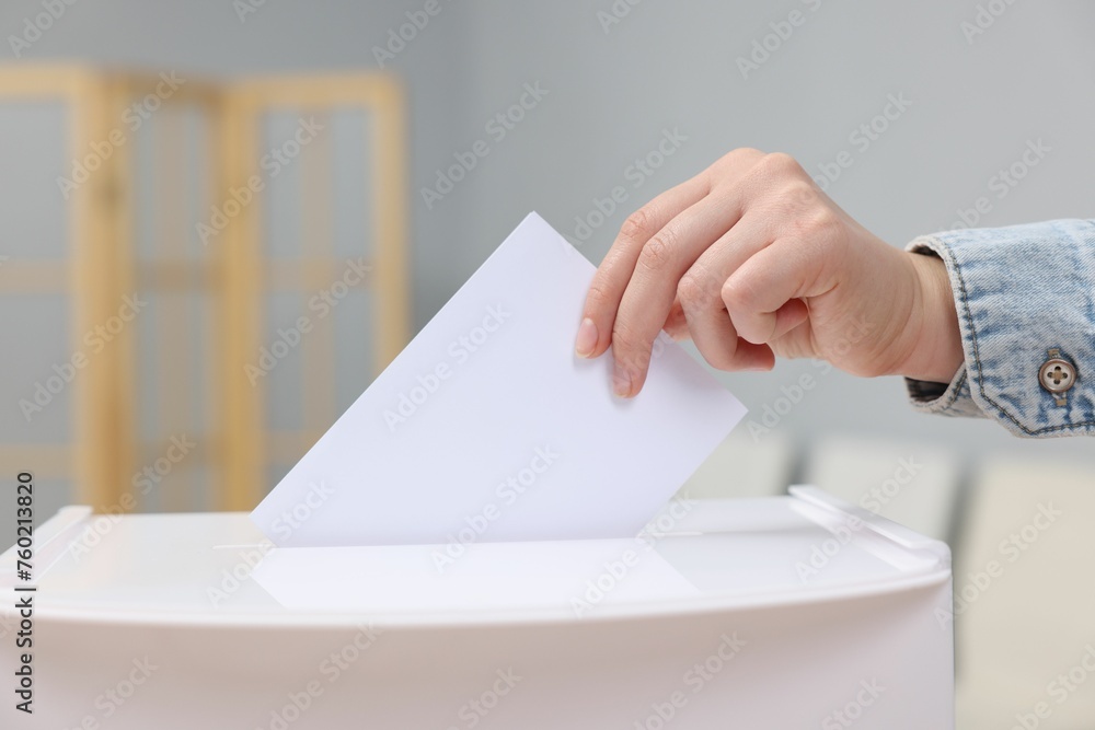Woman putting her vote into ballot box on blurred background, closeup Woman putting her vote into ballot box on blurred background, closeup