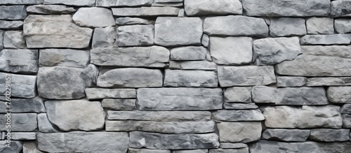 A detailed closeup of a stone wall constructed with grey bricks, showcasing a beautiful monochrome pattern of rectangular flagstones and brickwork building material