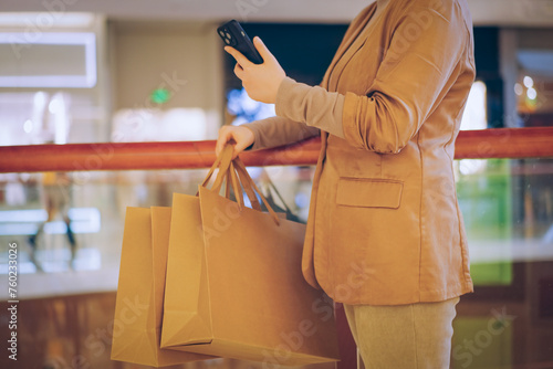 Consumer with Shopping Bags Using Smartphone