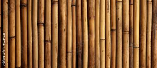 A closeup of a bamboo fence showcasing the intricate pattern of the wood stain and varnish. The shades of peach add a pop of color to the hardwood structure