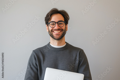 a man with glasses holding a laptop computer