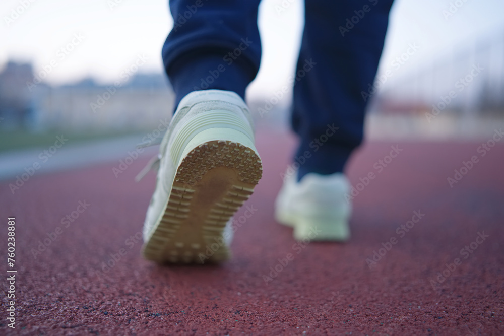 Close-Up of Feet Walking on Red Running Track