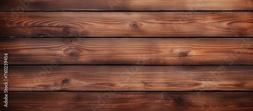 A closeup of a brown hardwood plank wall with a wood stain and varnish finish. The lumber creates a beautiful pattern with tints and shades in the flooring