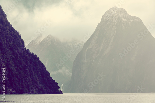 Photograph of mountains in clouds and mist viewed from the water in Milford Sound in Fiordland National Park on the South Island of New Zealand photo