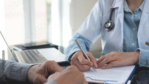 Female doctor writing a prescription for her patient. Docotr filling medical insurance claim form at medical clinic, healthcare and medicine concept, close up