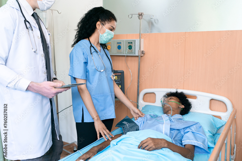 Obraz premium Doctor and African American patient talking in hospital ward about diagnosis and treatment for teenager in bed. Black specialist man with stethoscope consulting sick young adult