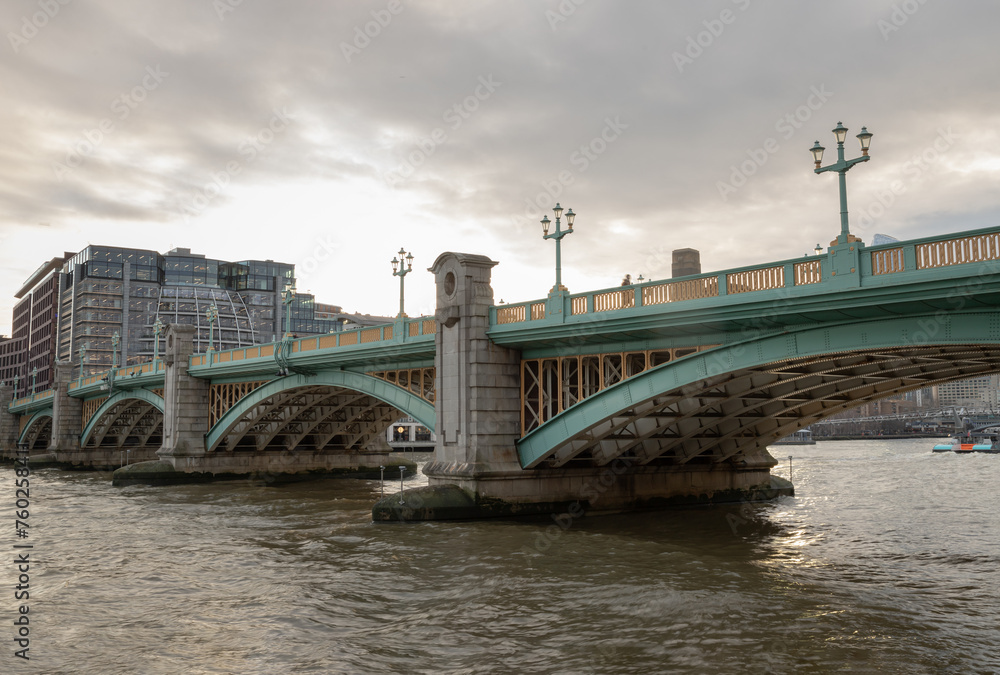 Fototapeta premium View of Southwark Bridge cross The River Thames in London. The side of a turquoise cast iron bridge, Curved steel Bridge, Space for text, Selective focus.