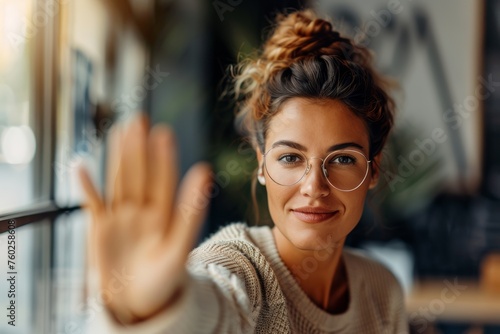 Woman with glasses reaching out to the camera, friendly and engaging. photo