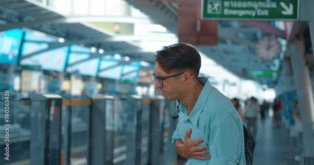 At metro station, man suddenly became ill and clutched heart. Young guy felt sharp pain in heart area and grabbed chest with hand. Cinematic shot of lonely person in public place with pain in heart. At metro station, man suddenly became ill and clutched heart. Young guy felt sharp pain in heart area and grabbed chest with hand. Cinematic shot of lonely person in public place with pain in heart.