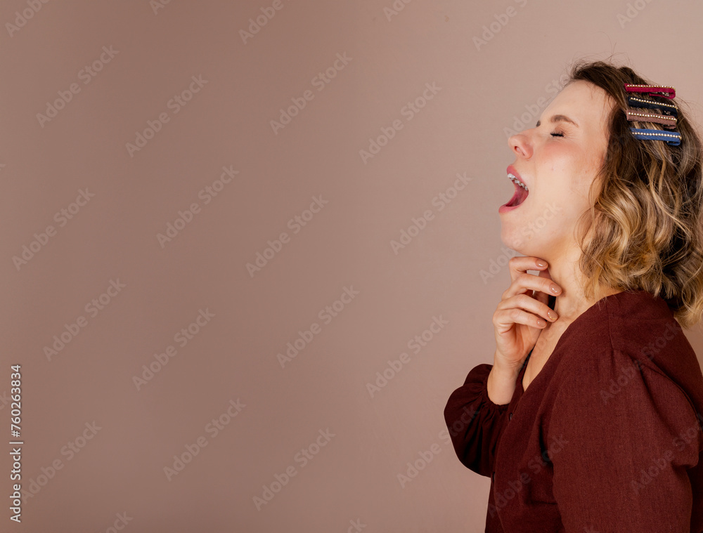 Young woman yawning with various hair accessories. Photo in studio with isolated background. Mental health. Young woman yawning with various hair accessories. Photo in studio with isolated background. Mental health.