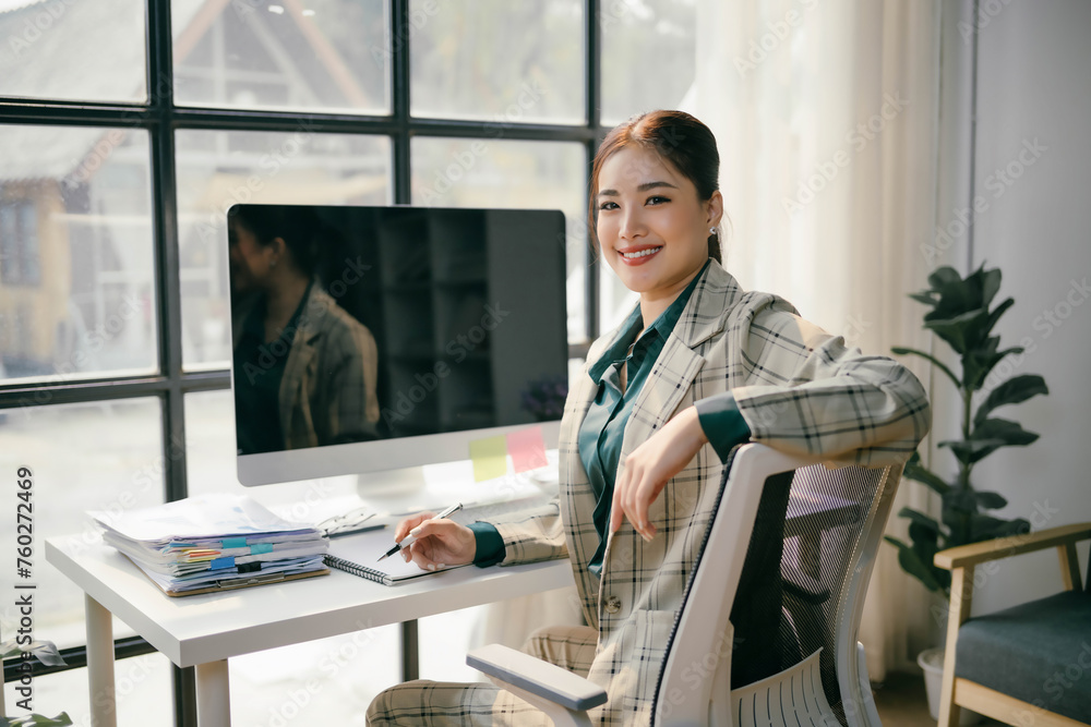 A woman is sitting at a desk with a computer monitor in front of her A woman is sitting at a desk with a computer monitor in front of her