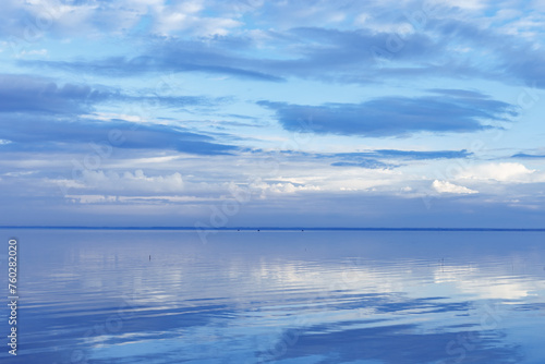White blue clouds over lake, symmetric sky and water background, cloudscape on lake. Nature abstract, cloudy sky reflected on water, calm tranquil concept, aesthetic panoramic view