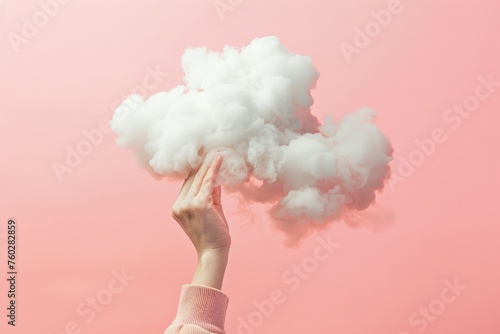 a womans hand is holding a cloud against pink background