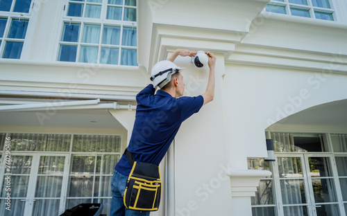 A technician installs a CCTV camera on the facade of a residential building. photo