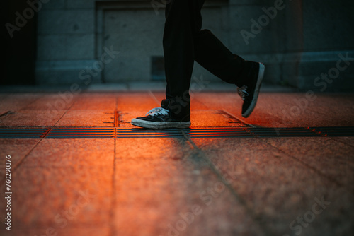Legs and shoes of people waling in the street with red light glow on the ground