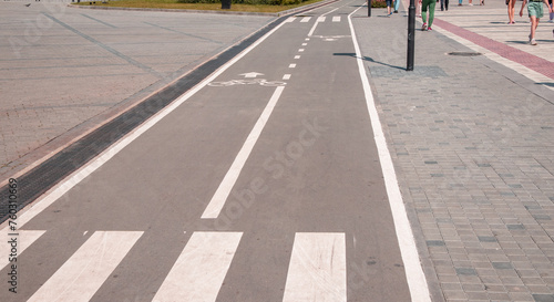 A sign of a bicycle path and pedestrian crossing on the asphalt in a city park, close-up