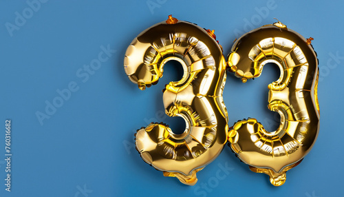 Banner with number 33 golden balloon with copy space. thirty three years anniversary celebration concept on a blue background. © Uuganbayar