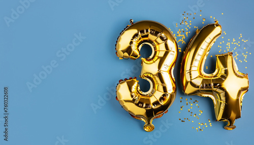 Banner with number 34 golden balloon with copy space. thirty four years anniversary celebration concept on a blue background. photo