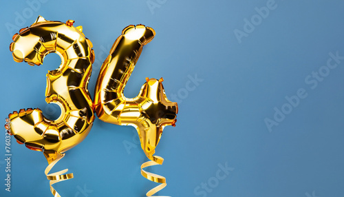 Banner with number 34 golden balloon with copy space. thirty four years anniversary celebration concept on a blue background. photo