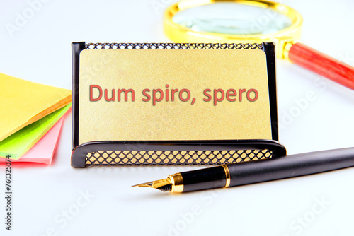 Dum Spiro Spero - latin phrase means While I Breath, I Hope. on a gold business card with highlighted text photo