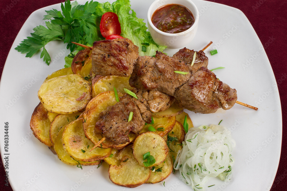 Delicious kebab with fried potatoes on a plate, menu for a restaurant Delicious kebab with fried potatoes on a plate, menu for a restaurant