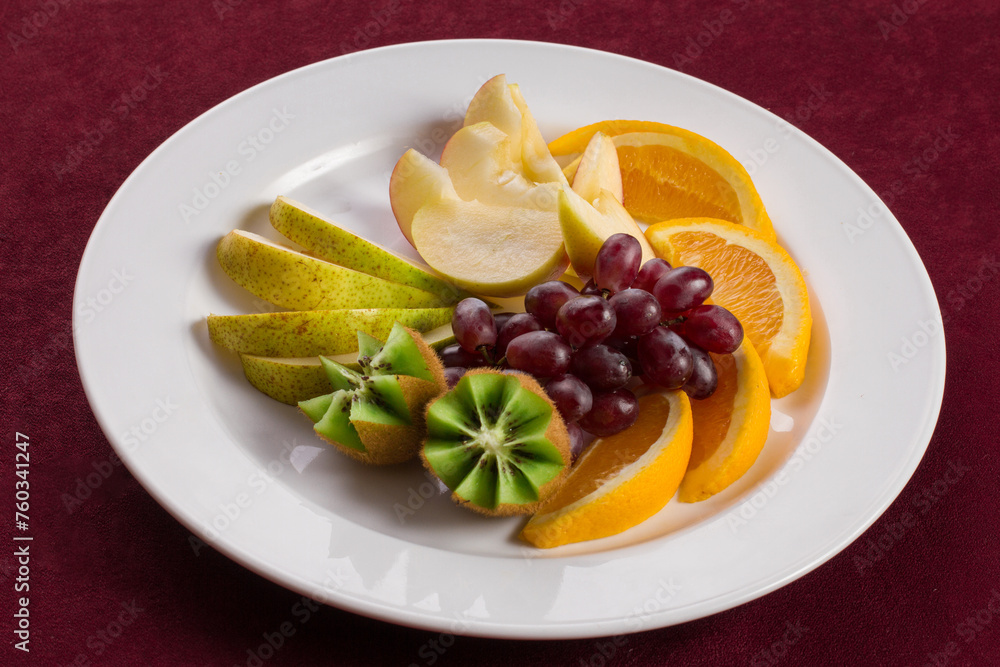 A plate of tropical fruits standing on red velvet A plate of tropical fruits standing on red velvet