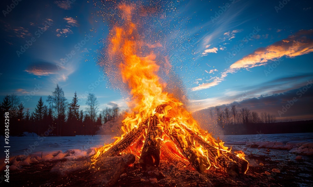 A fire is burning in a pile of wood, with the sky in the background