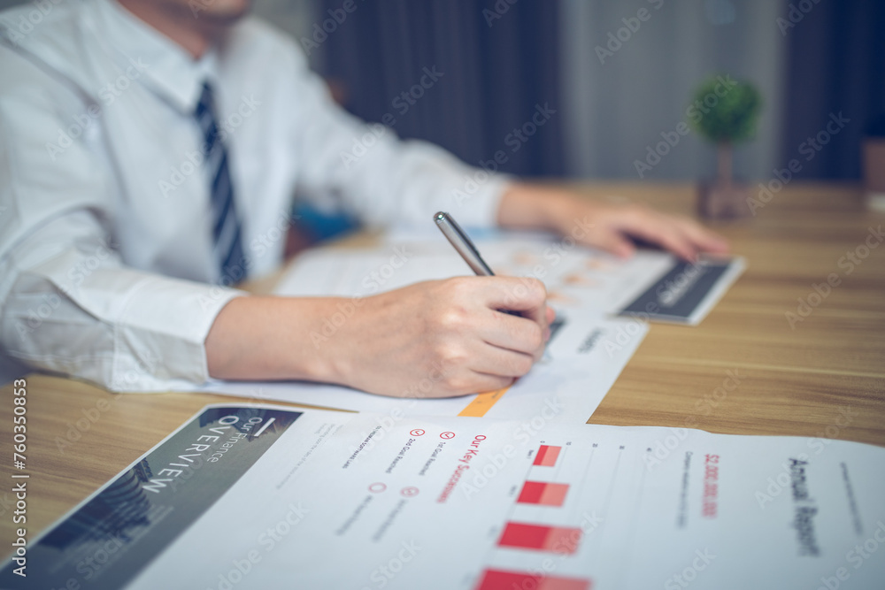Close-up of a businessperson reviewing graphs and charts, focusing on document analysis Close-up of a businessperson reviewing graphs and charts, focusing on document analysis