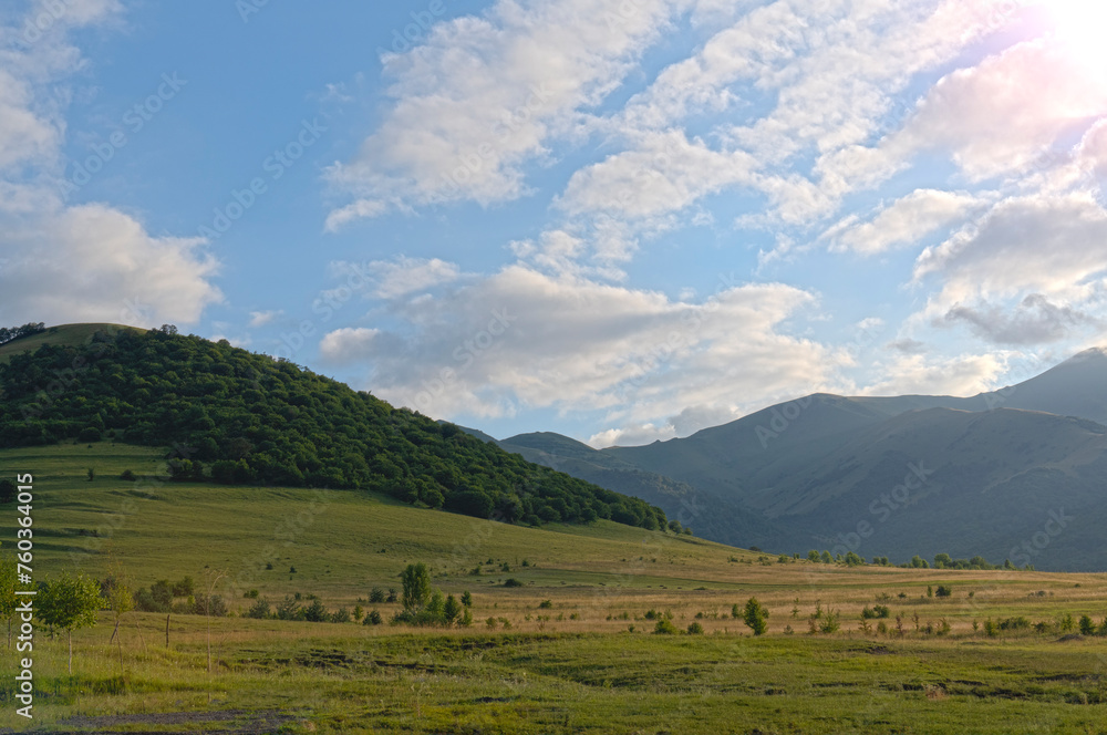 mountainous countryside landscape in spring grassy meadow on top of a hill mountain ridge sunny weather with clouds on the blue sky mountainous countryside landscape in spring grassy meadow on top of a hill mountain ridge sunny weather with clouds on the blue sky