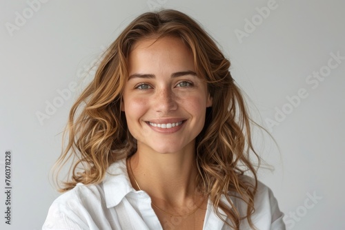 A woman with long brown hair and a white shirt is smiling