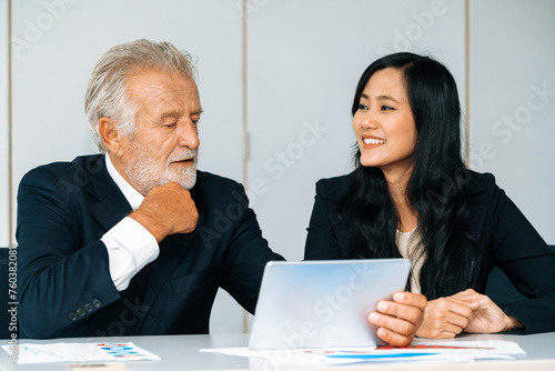 Senior executive manager and young businesswoman working in meeting room in the office. The woman is secretary or translator. International business language translation concept. uds