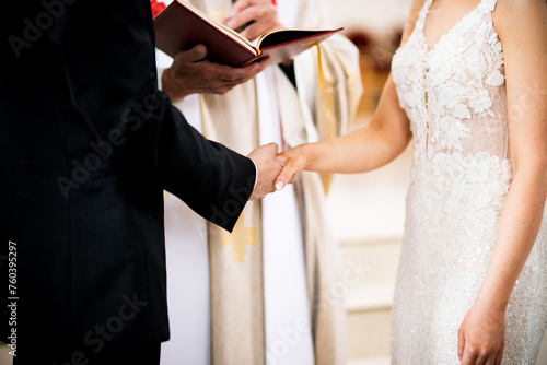Marriage vows during wedding ceremony in a Catholic Church exchanging wedding rings bride and groom intertwined hands