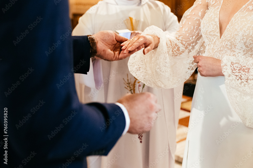 Exchange of wedding rings in a church couple holding hands during catholic ceremony