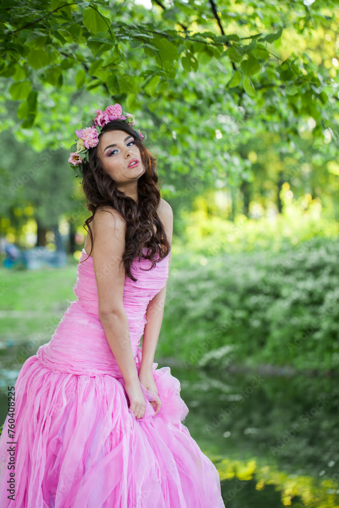 Charming young adult lady with with long hair, make-up and pink flower in spring park. Beauty woman portrait