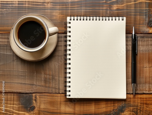 An empty notebook with a pen on a wooden surface next to a cup of black coffee.