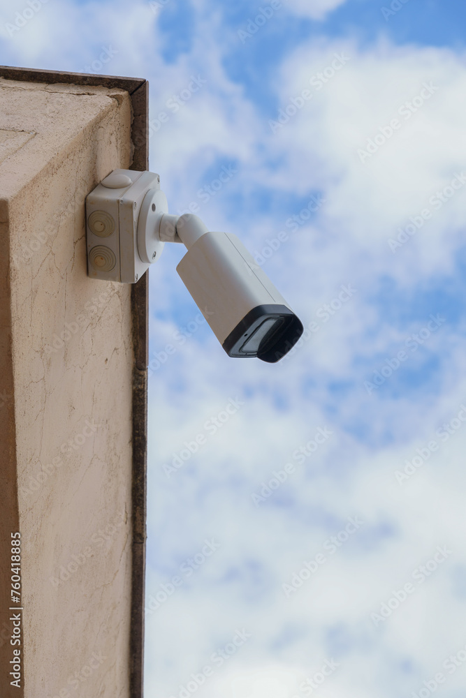 surveillance camera on a wall with a cloudy sky in the background surveillance camera on a wall with a cloudy sky in the background